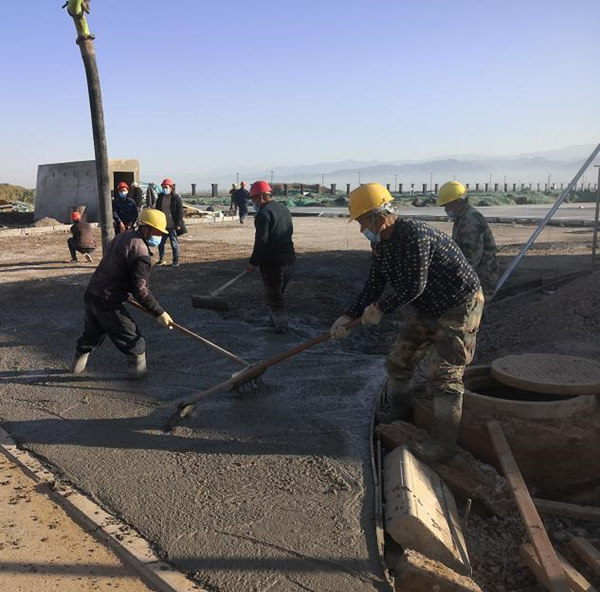 宝鸡蟠龙新区污水处理厂项目施工人员对厂区道路面层进行混凝土浇筑作业_副本.jpg